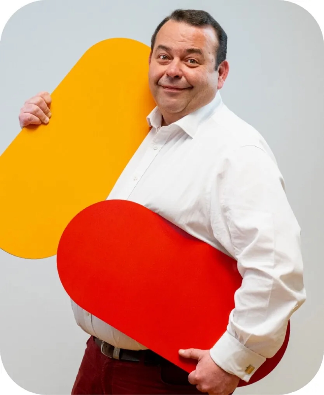 Cheerful founder holding yellow and red brand shapes in studio — corporate photo by Best Alex Shots, Vienna