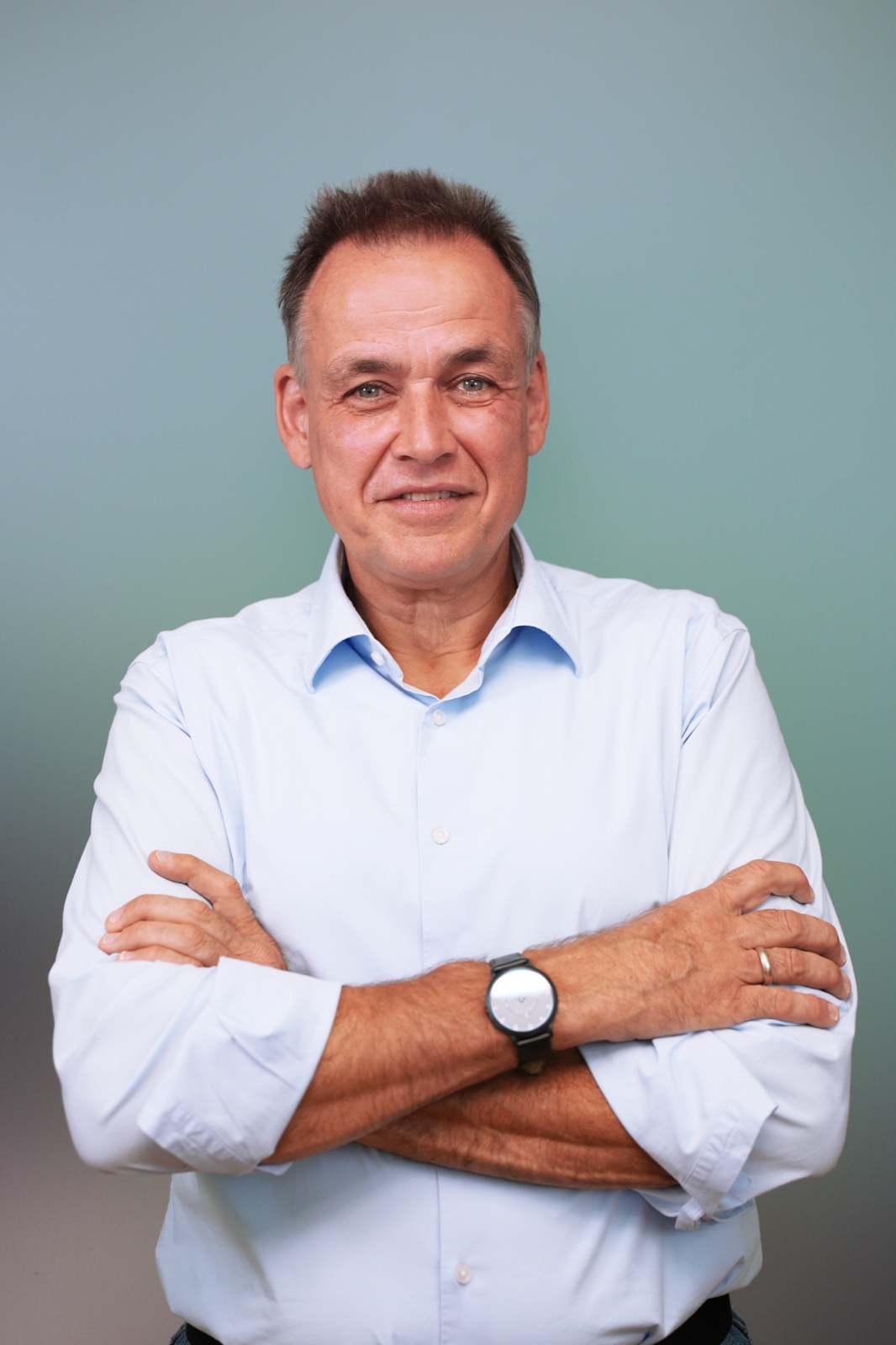 Confident male team member in light blue shirt with arms crossed — studio corporate portrait by Best Alex Shots, Vienna