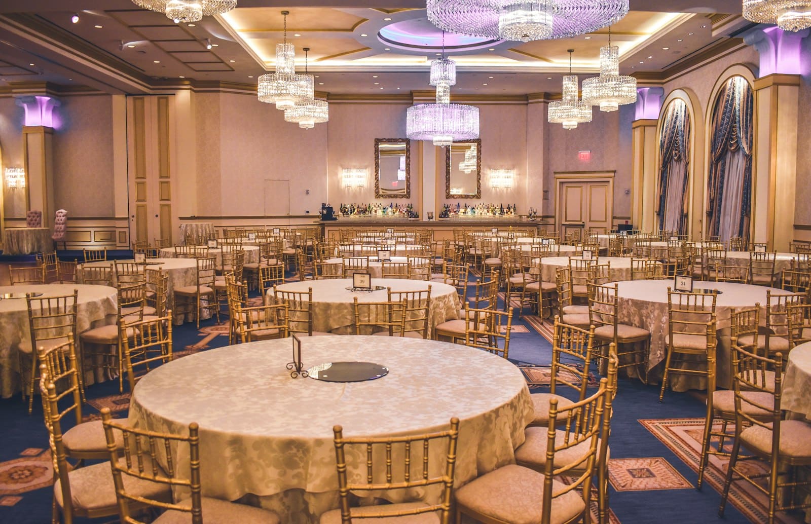 Empty ballroom with chandeliers and round tables set before a gala event