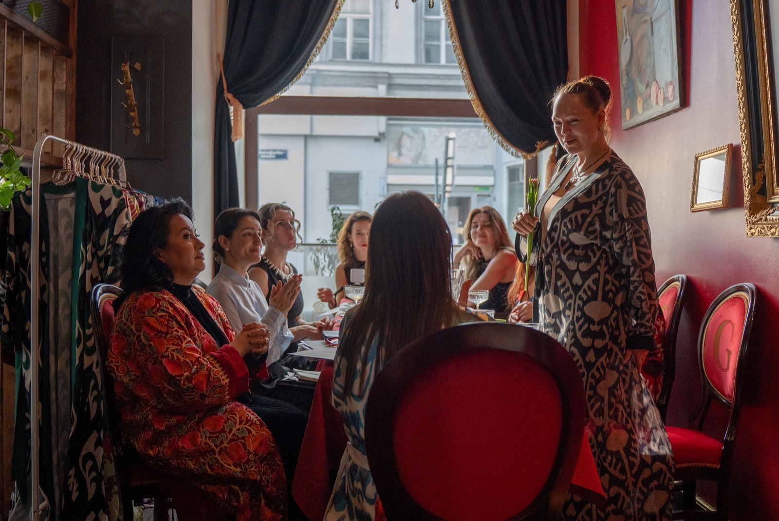 Designer presenting ikat collection to guests at a Vienna restaurant fashion event with window view of the street — event photography by Best Alex Shots