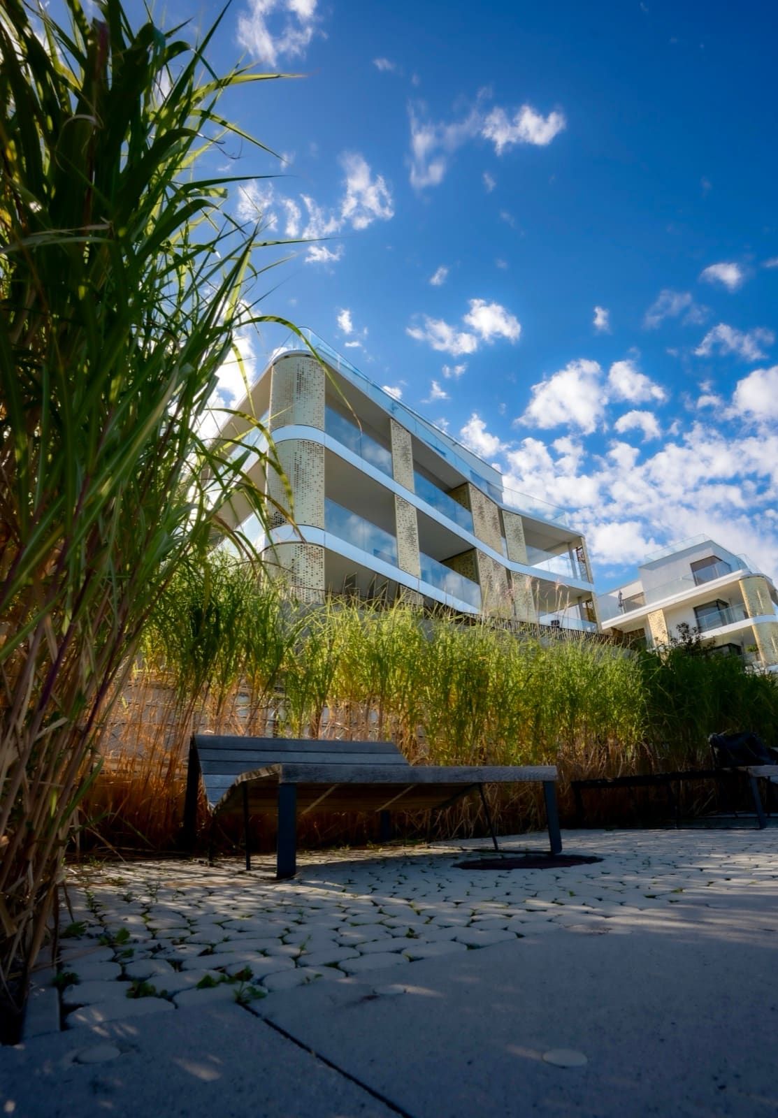 Modern residential building with golden facade, grass and bench in the foreground, Best Alex Shots, Vienna