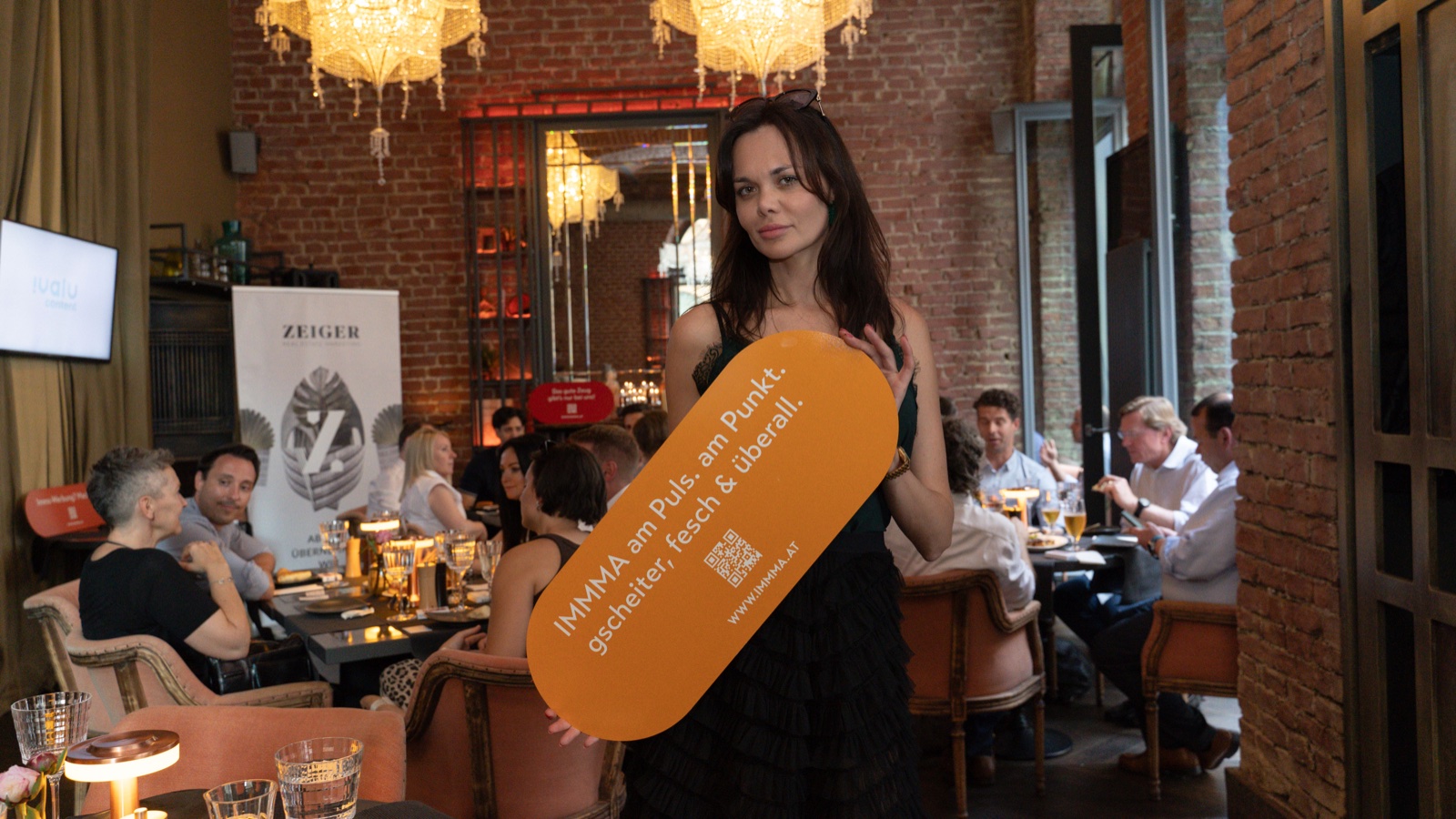 Guest with IMMMA orange brand prop at restaurant event, Vienna — event photography by Best Alex Shots