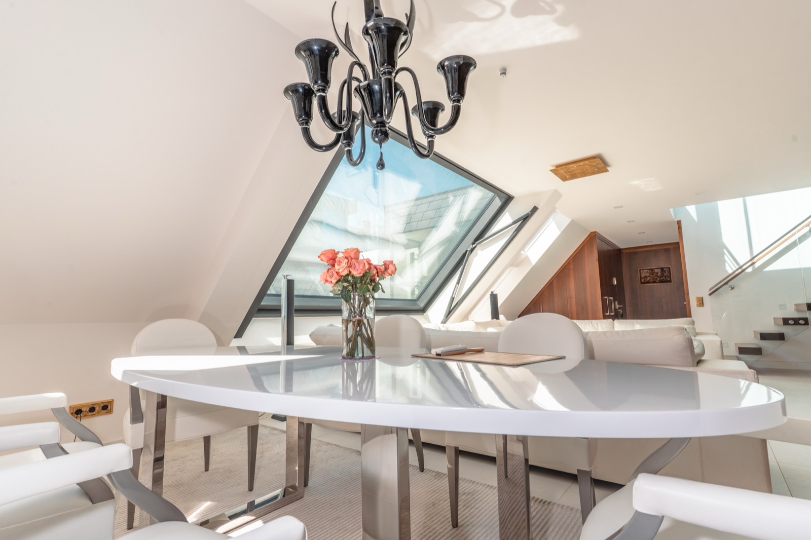 Luxury penthouse dining area with black Murano-style chandelier, glossy white round table and angled skylight window, Vienna — Best Alex Shots interior photography